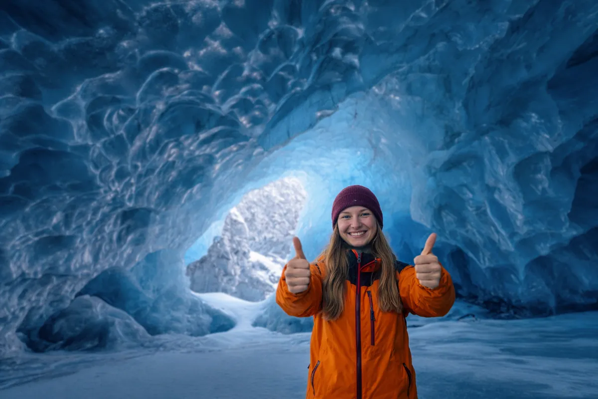 Visitor giving two thumbs up inside a blue ice cave in Vatnajökull glacier, Iceland